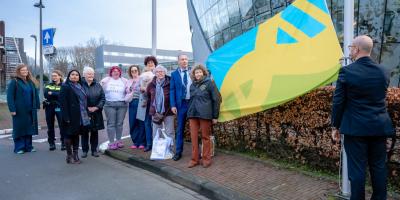 Belangstellenden staan voor het gemeentehuis van Alphen aan de Rijn en kijken hoe waarnemend burgemeester Erik van Heijningen de vlag van de rechten van de mens hijst.